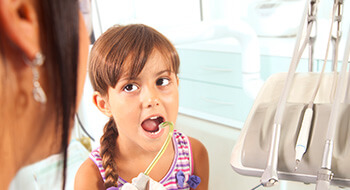 Young girl in dental chair looking at assistant