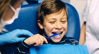 A young boy using a toothbrush on his teeth while at the dentist office