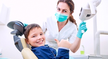 A young boy giving a thumbs up with his dentist next to him
