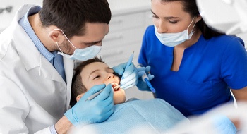 A dentist and dental hygienist perform a thorough check of a young boy’s smile