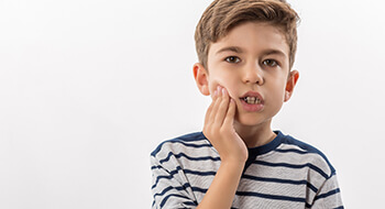 Young boy holding cheek in pain