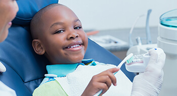 Smiling young boy practicing his tooth brushing