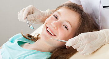 Young girl receiving treatment in dental chair