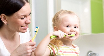  A little girl and her mom brushing their teeth at home