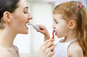 A mother and daughter brush each other’s teeth.